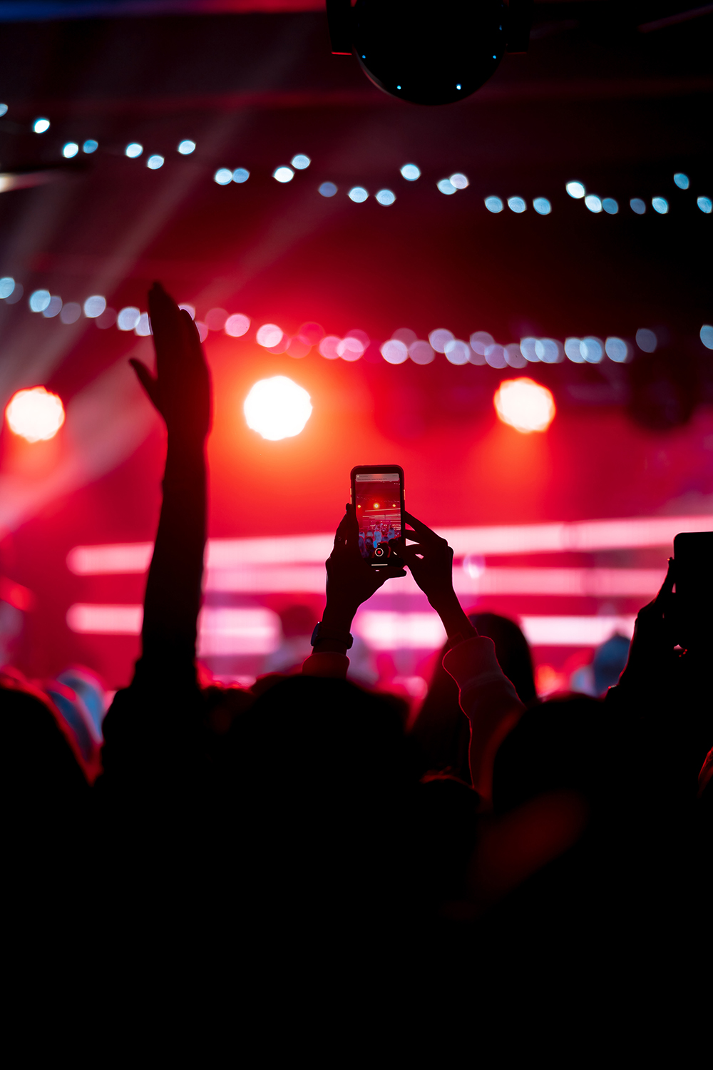 Person close up of recording video with smartphone during a concert.